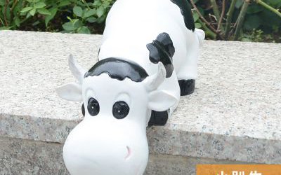 園林一只趴著的玻璃鋼卡通奶牛雕塑